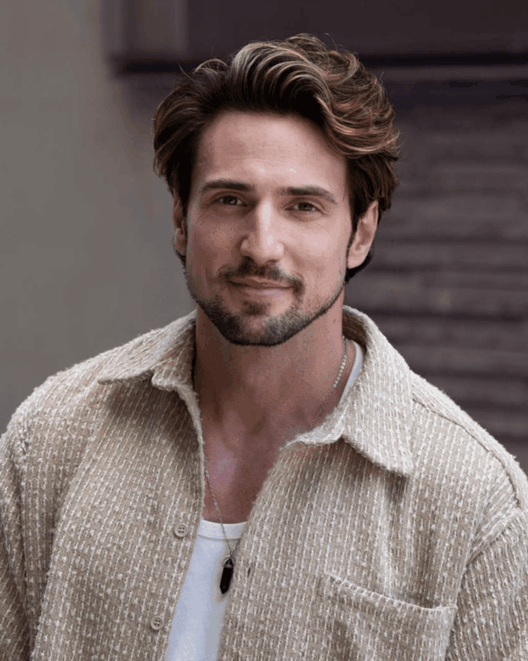 A focused portrait of a stylish man with tousled hair, wearing a textured beige shirt, set against a neutral background, capturing a modern and approachable vibe in a Pacific Northwest urban environment.