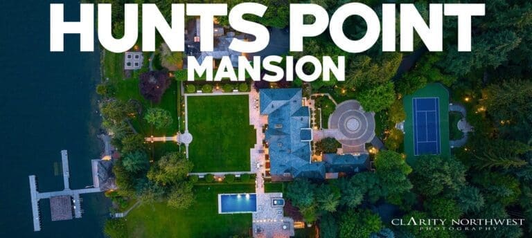 Aerial view of a luxurious mansion in Hunts Point, Washington, featuring expansive green lawns, a swimming pool, and a tennis court, surrounded by lush landscaping, showcasing an elegant and serene atmosphere.