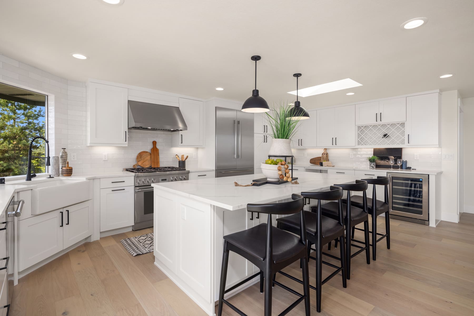 Modern kitchen with white cabinetry, stainless steel appliances, and a large island featuring black bar stools, located in the Pacific Northwest.