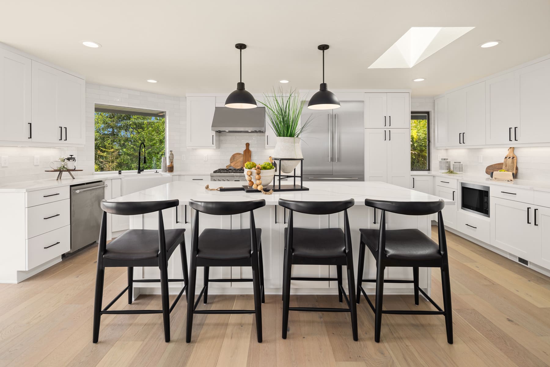 Modern kitchen with white cabinetry, sleek black accents, and a spacious island featuring bar seating, located in the Pacific Northwest.