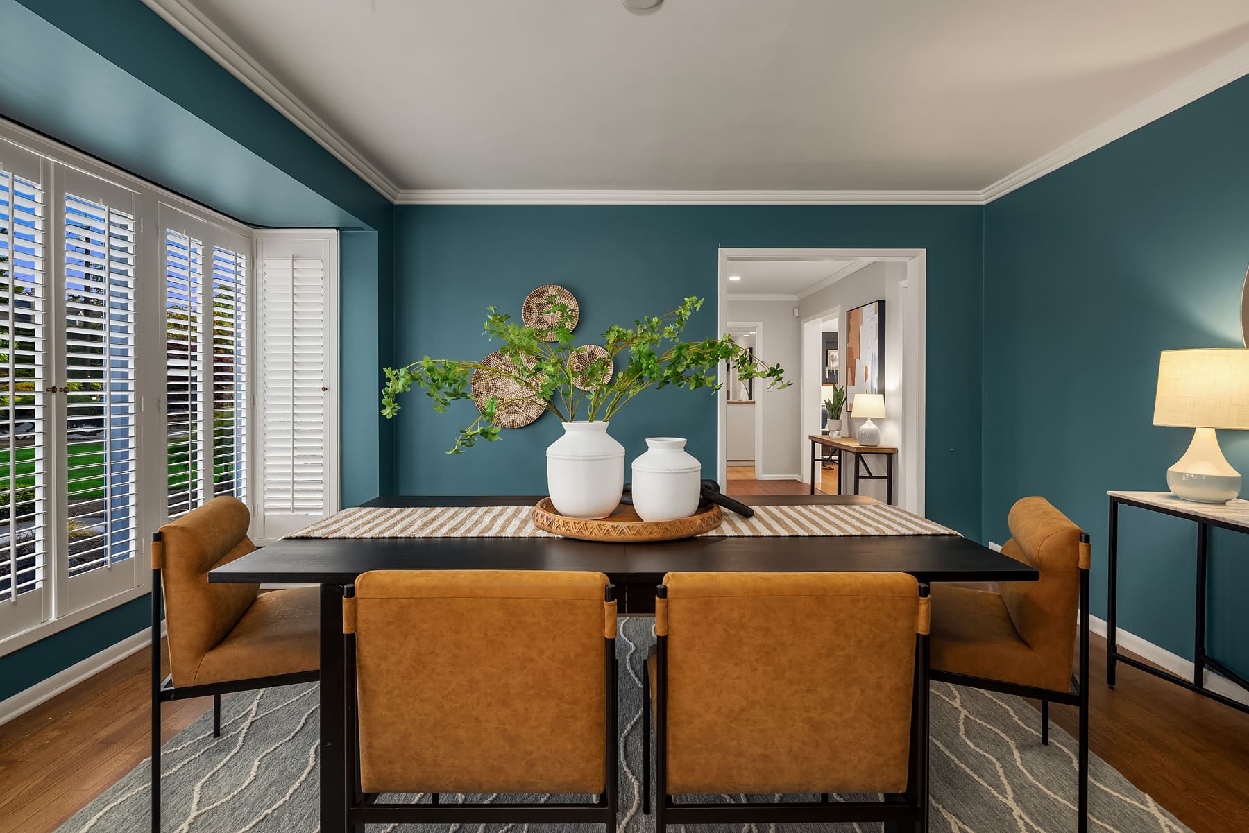 Elegant dining room with teal walls, modern wooden table, and stylish leather chairs, featuring decorative plants and artwork, located in the Pacific Northwest.