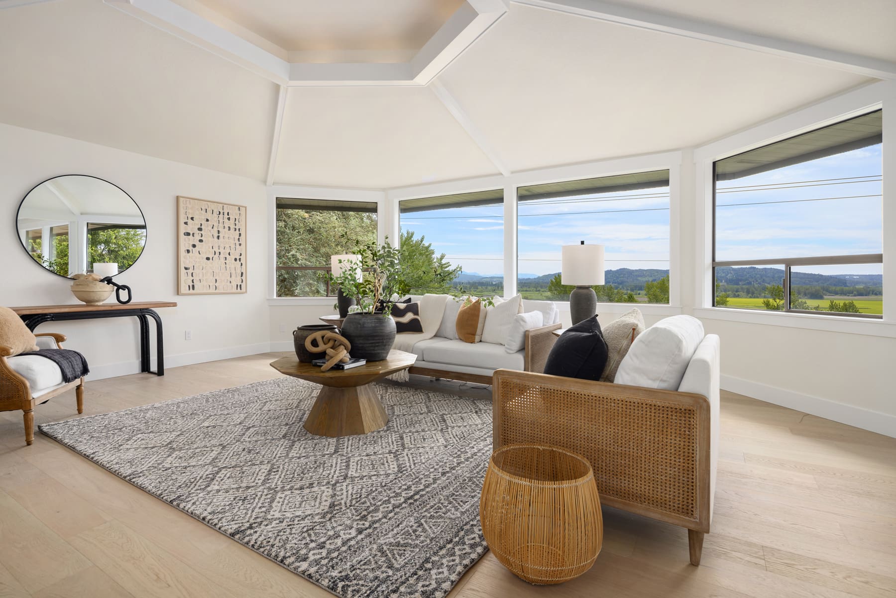 Bright and airy modern living room featuring a stylish sectional sofa, natural wood accents, and panoramic windows with scenic views, located in the Pacific Northwest.