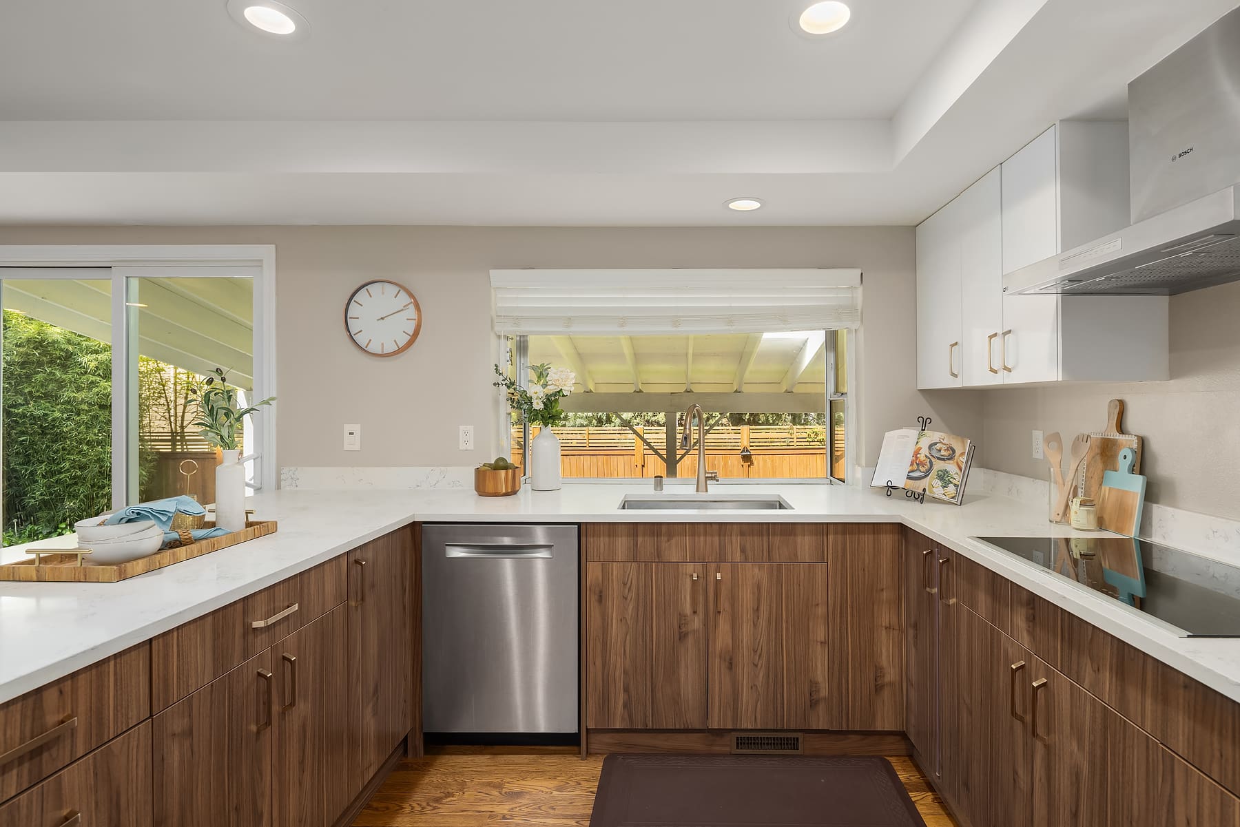 Modern kitchen with sleek wood cabinetry, quartz countertops, and stainless steel appliances, featuring large windows that offer a view of the outdoor space, located in the Pacific Northwest.
