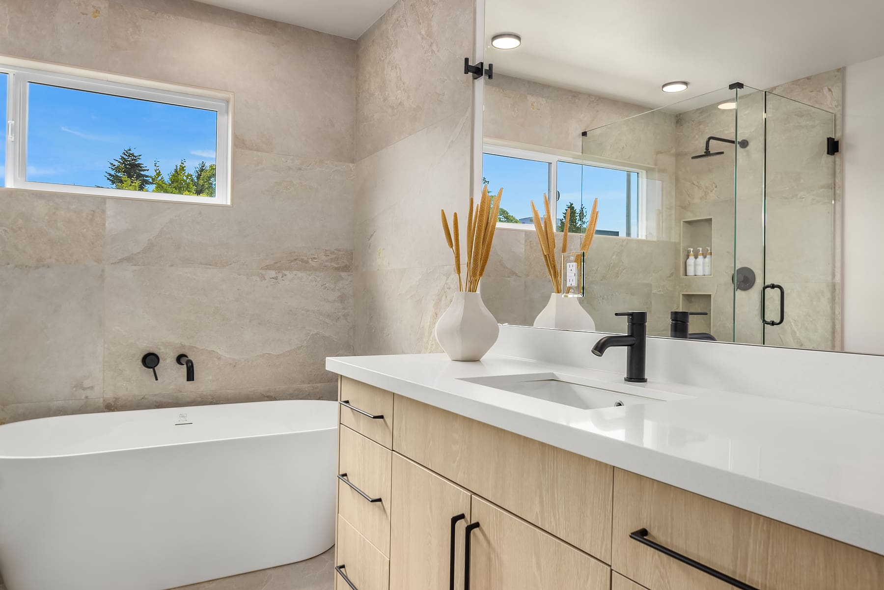 Modern bathroom featuring a freestanding tub, sleek black fixtures, and natural stone walls, showcasing a serene atmosphere in the Pacific Northwest.