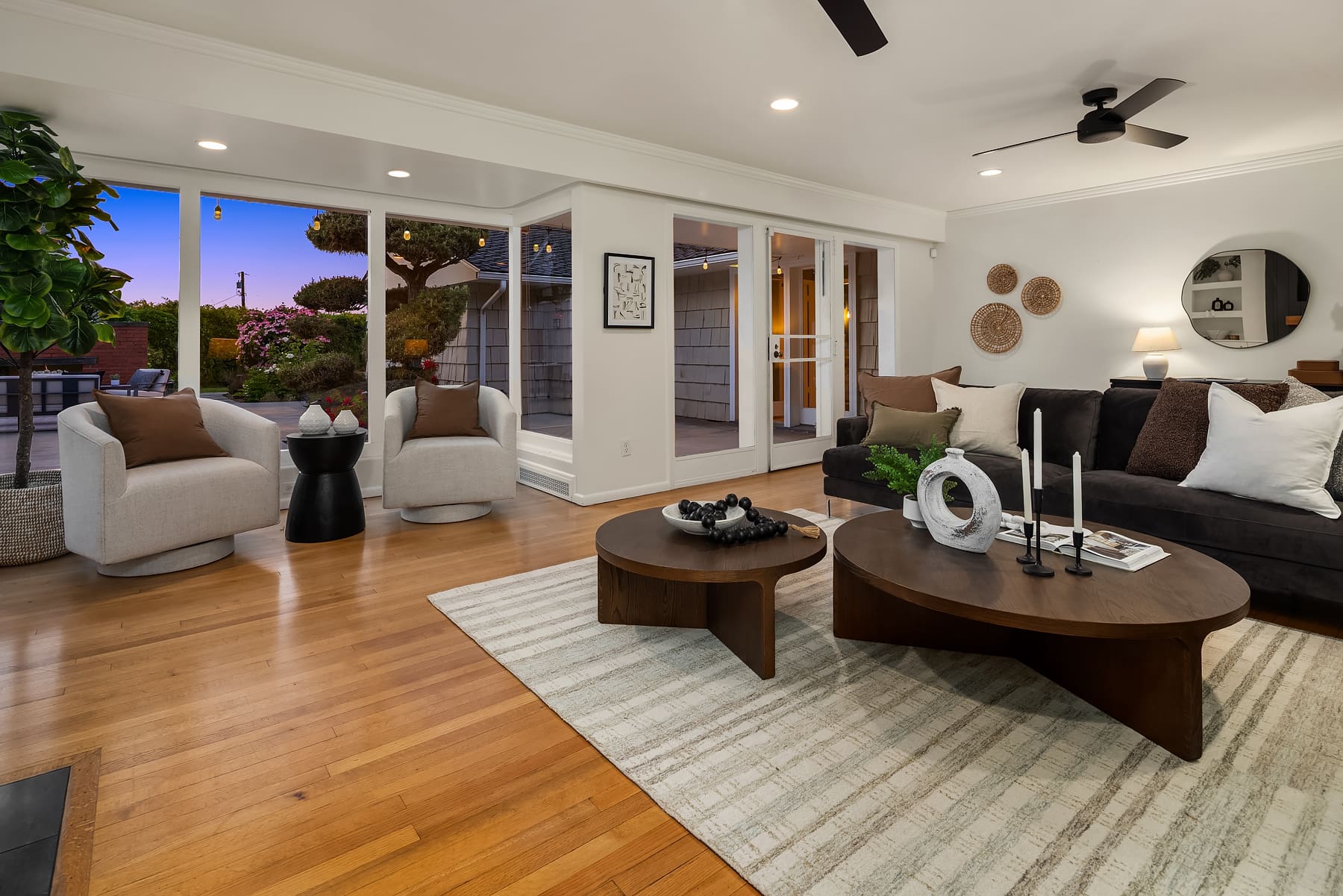 Modern living room with elegant design features, including plush seating, stylish decor, and large windows showcasing a garden view at twilight, located in the Pacific Northwest.