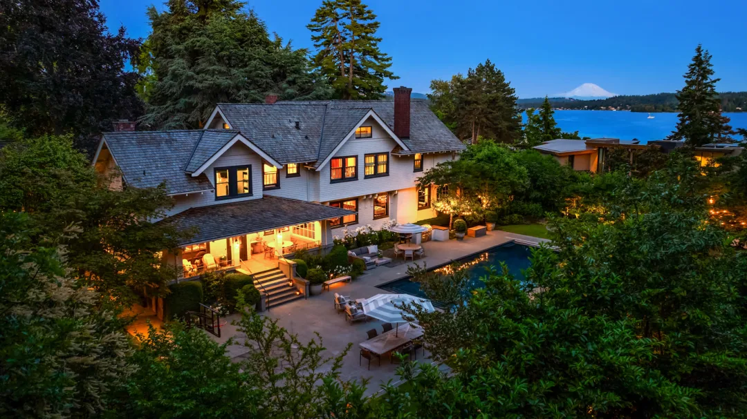 Stunning exterior view of a modern home in the Pacific Northwest, featuring lush greenery, a swimming pool, and warm evening lighting, creating an inviting atmosphere.