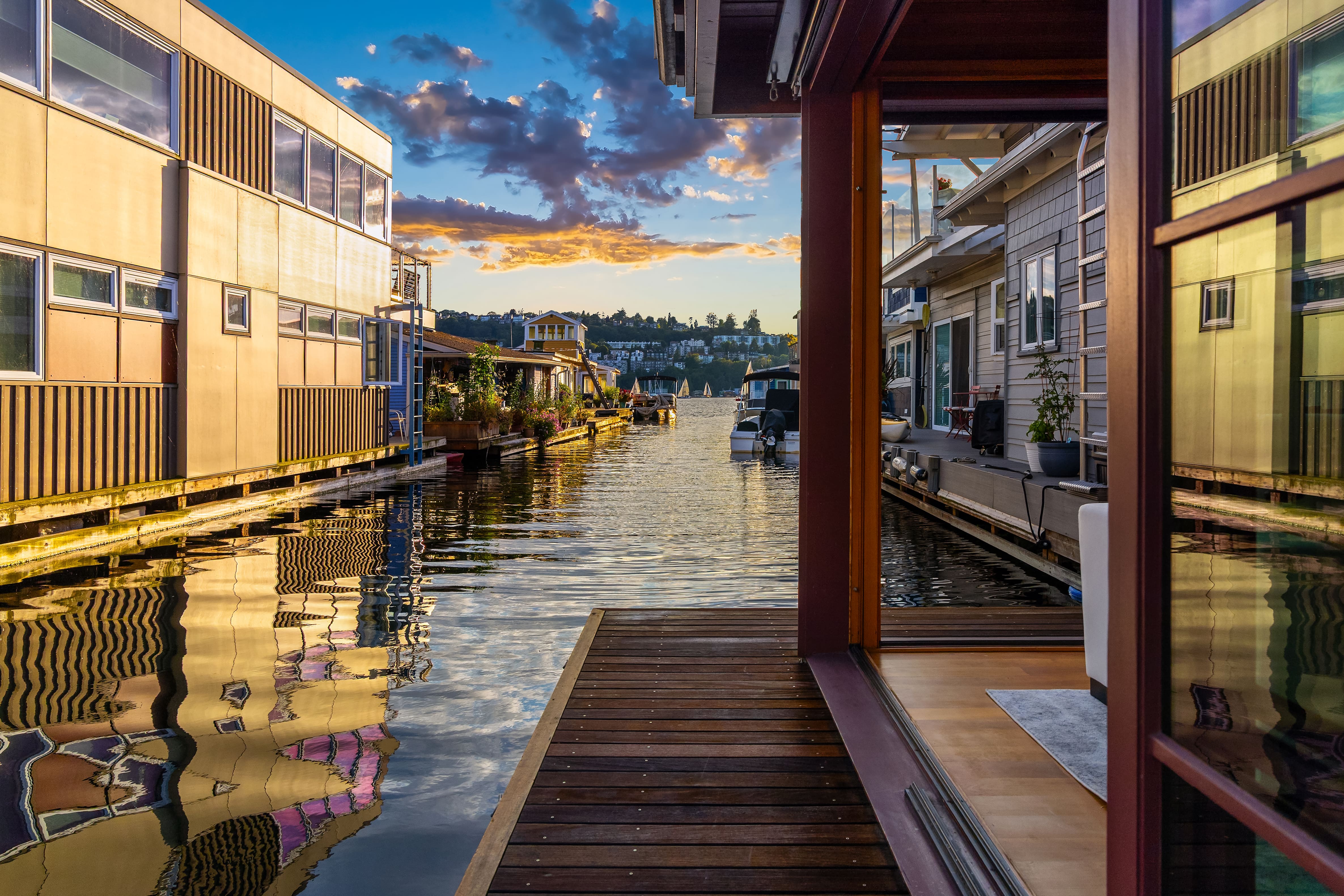 Scenic view of a tranquil houseboat canal in Seattle, showcasing modern architectural designs and vibrant reflections on the water at sunset.
