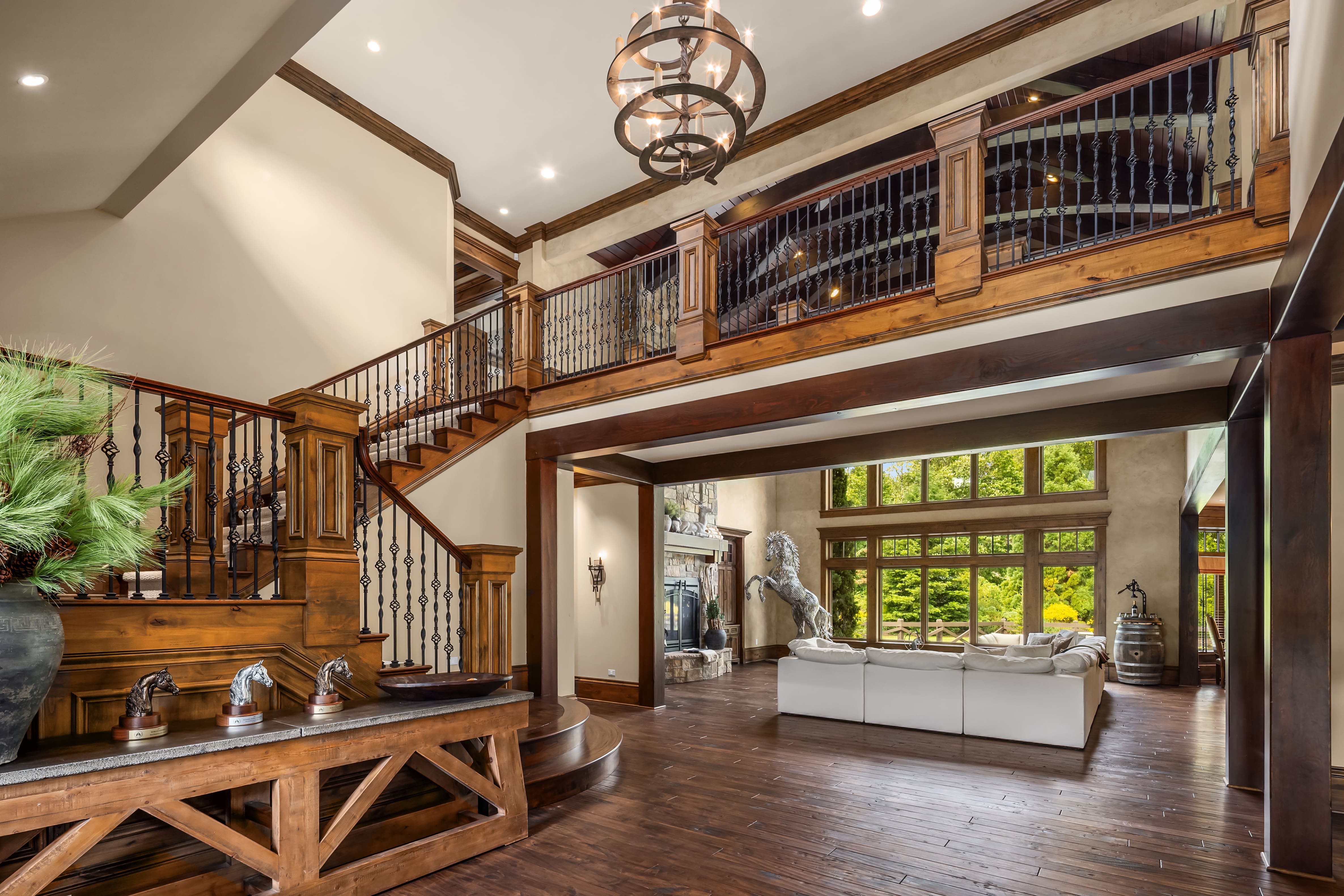 Spacious entryway and living room featuring elegant wooden finishes, a grand staircase, and large windows allowing natural light, located in the Pacific Northwest.