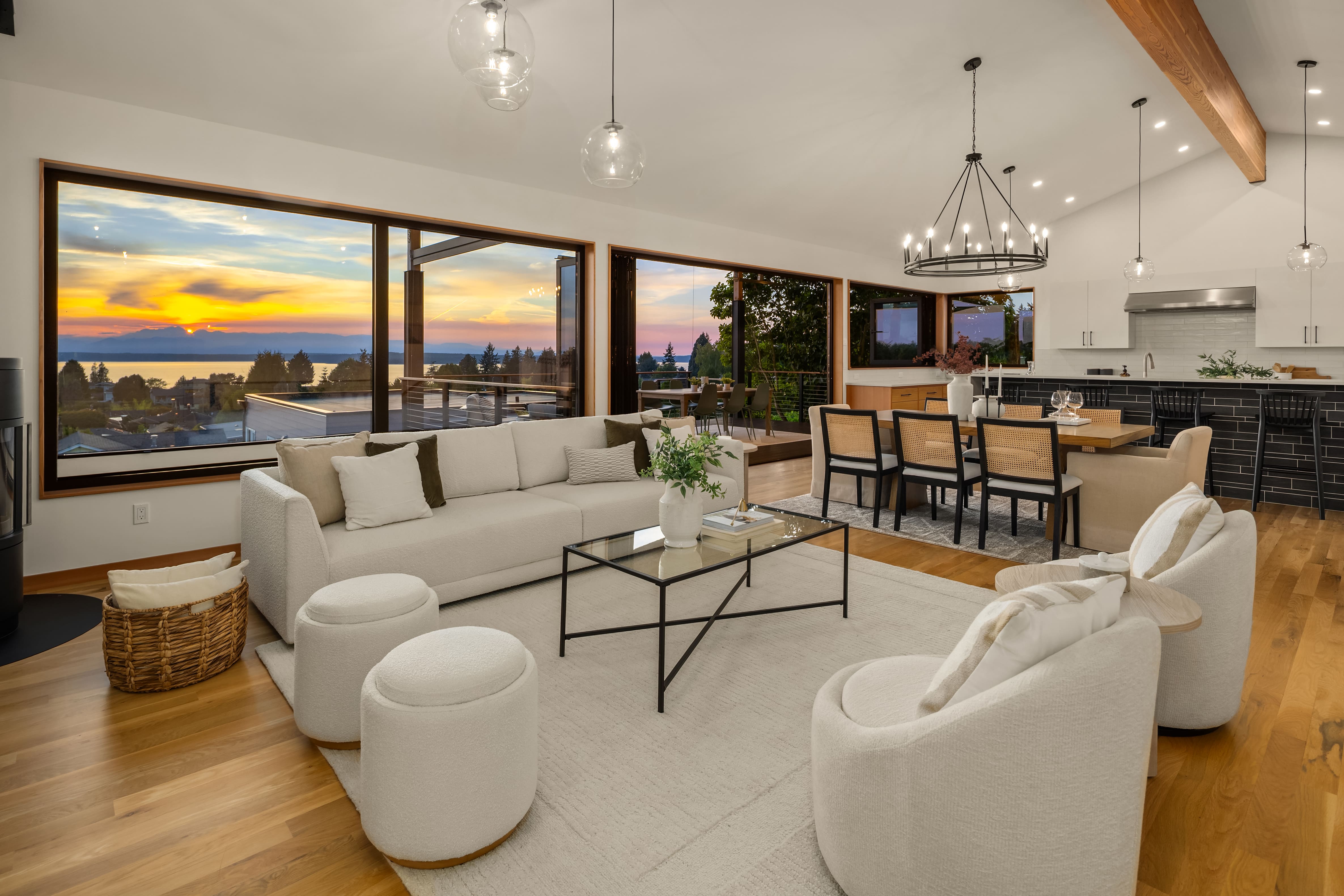 Modern living room with large windows showcasing a stunning sunset view, featuring a cozy white sectional sofa, stylish accent chairs, and a sleek coffee table, located in the Pacific Northwest.