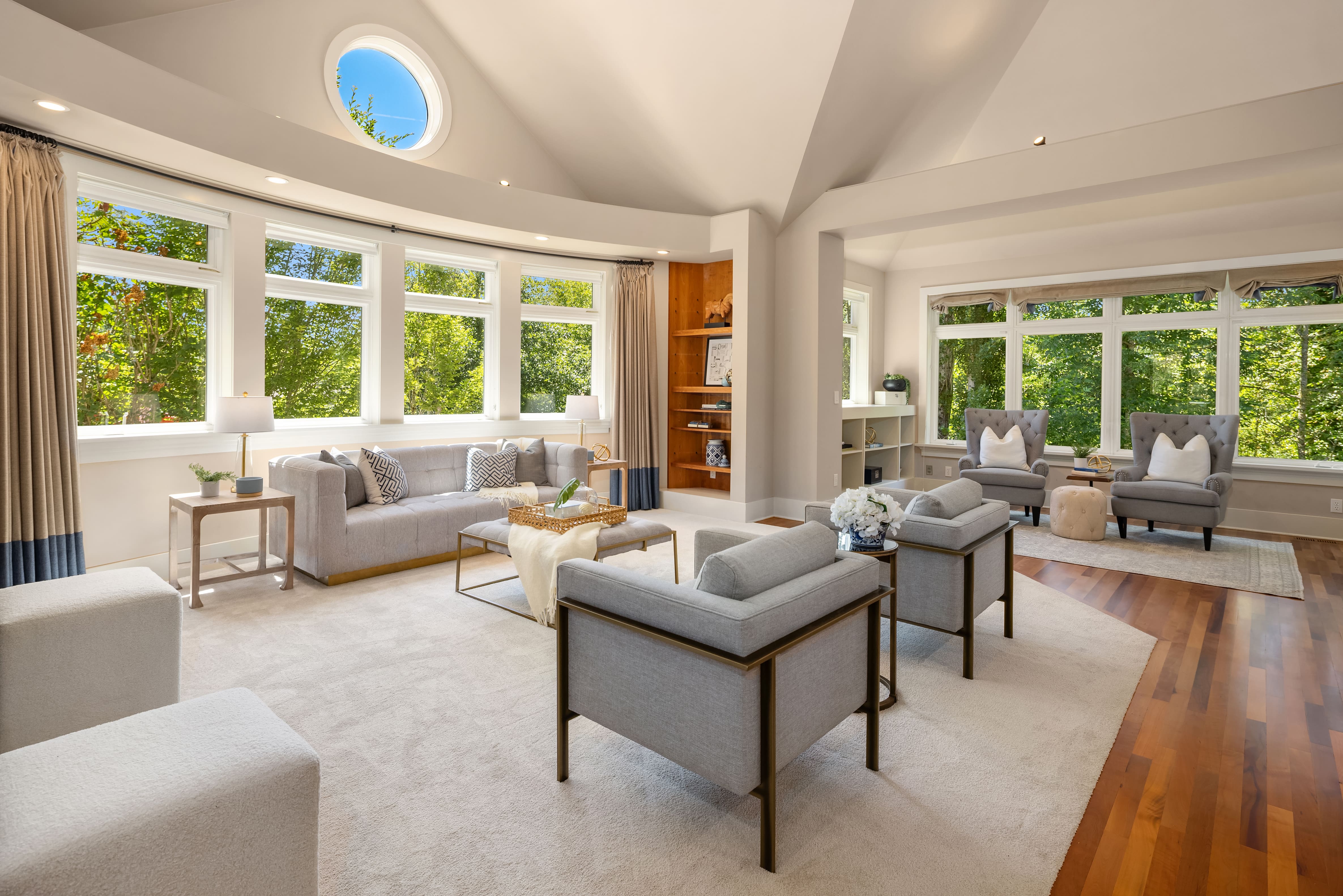 Bright and airy modern living room featuring large windows, plush gray sofas, and elegant decor, located in the Pacific Northwest.