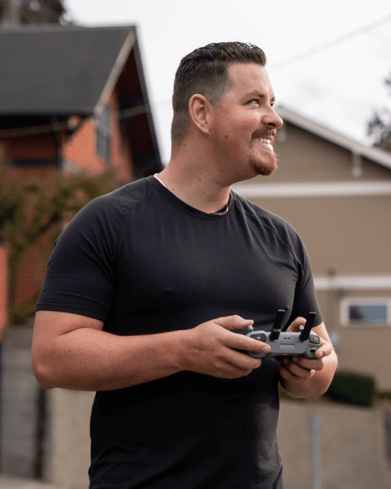 Michael Clark. A man operating a drone in an outdoor residential area, showcasing a modern suburban neighborhood in the Pacific Northwest.