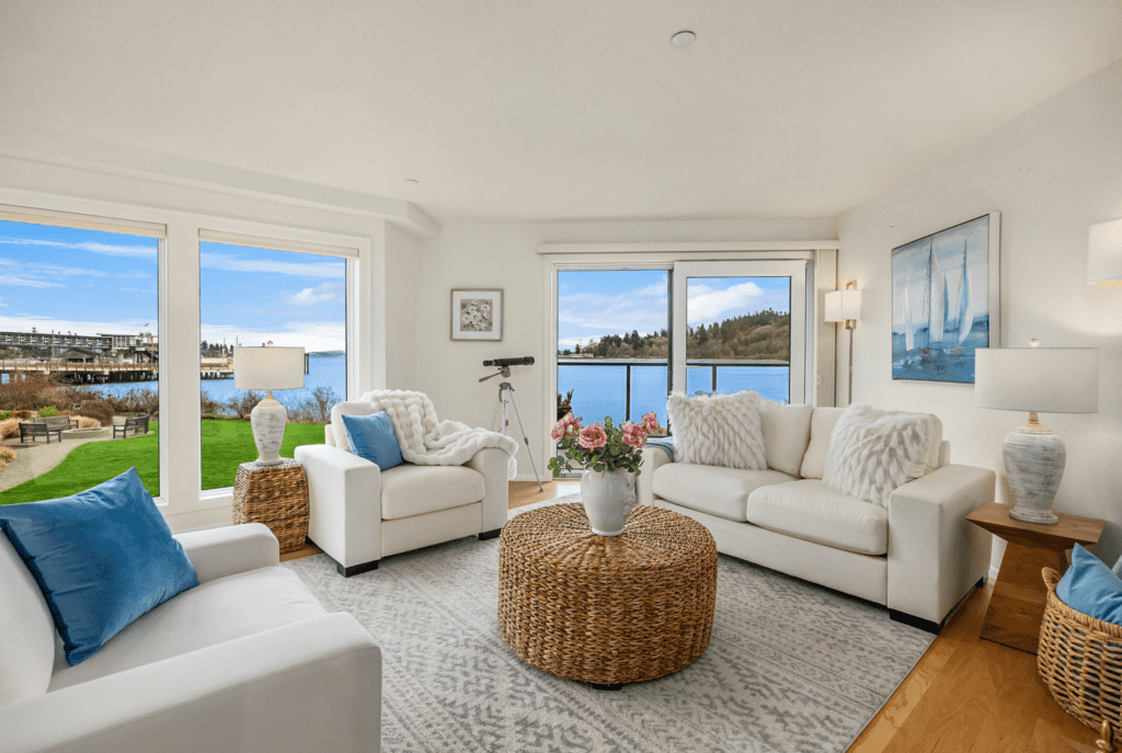 Bright and airy living room with modern white furnishings and coastal decor, featuring large windows that offer stunning views of the waterfront in the Pacific Northwest.