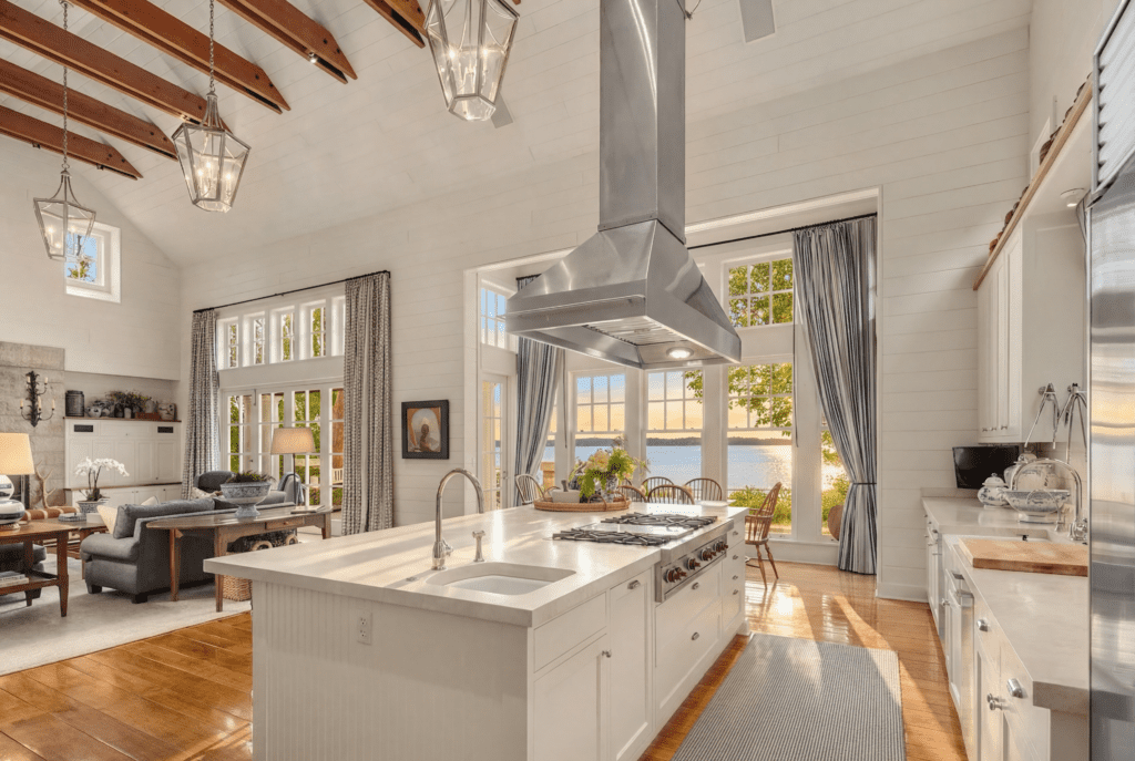 Spacious modern kitchen with high ceilings, exposed wooden beams, and large windows showcasing waterfront views, located in the Pacific Northwest.