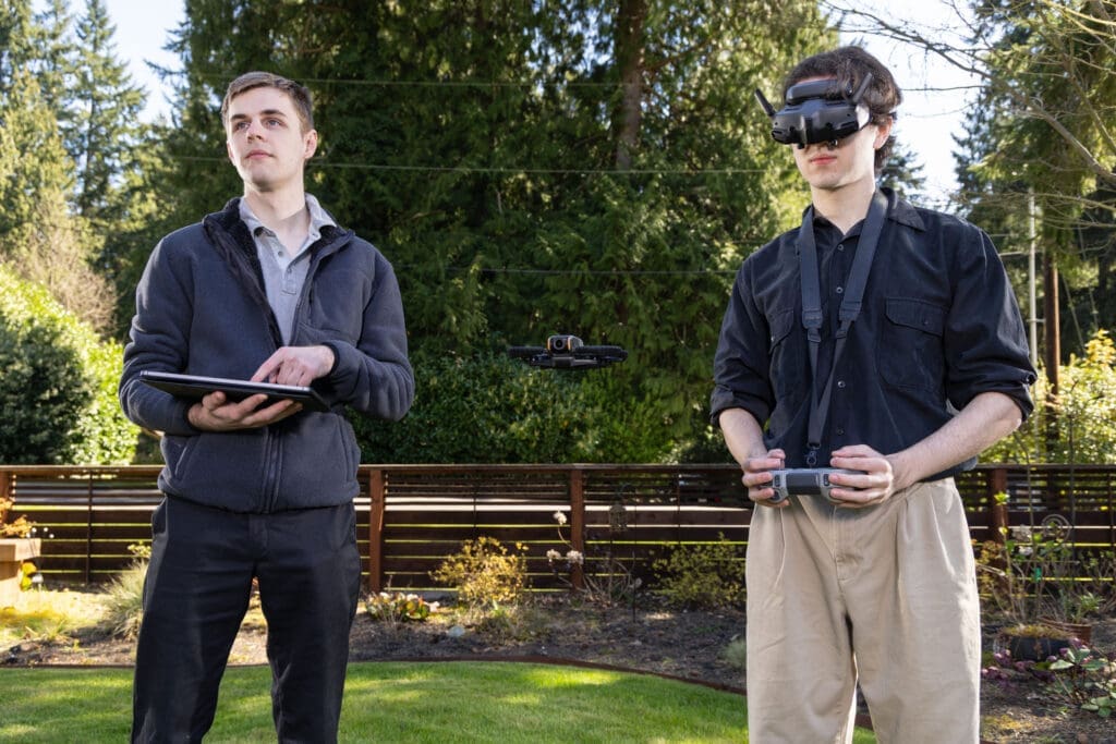 Two men operating a drone in a lush backyard, showcasing modern technology in real estate photography, located in the Pacific Northwest.